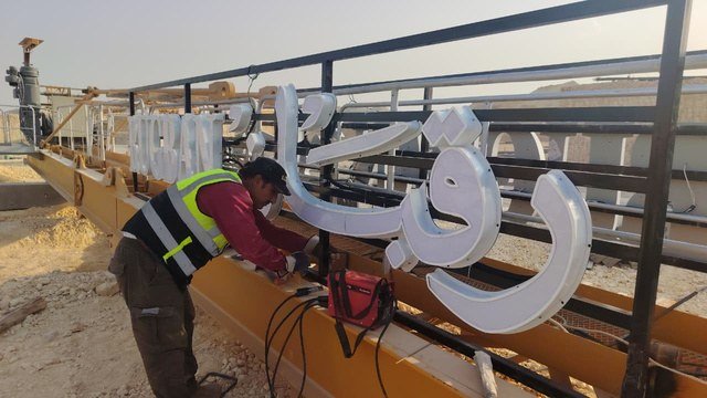 عمال ينفذون تركيب حروف لافتة كبيرة / Workers installing large signage letters